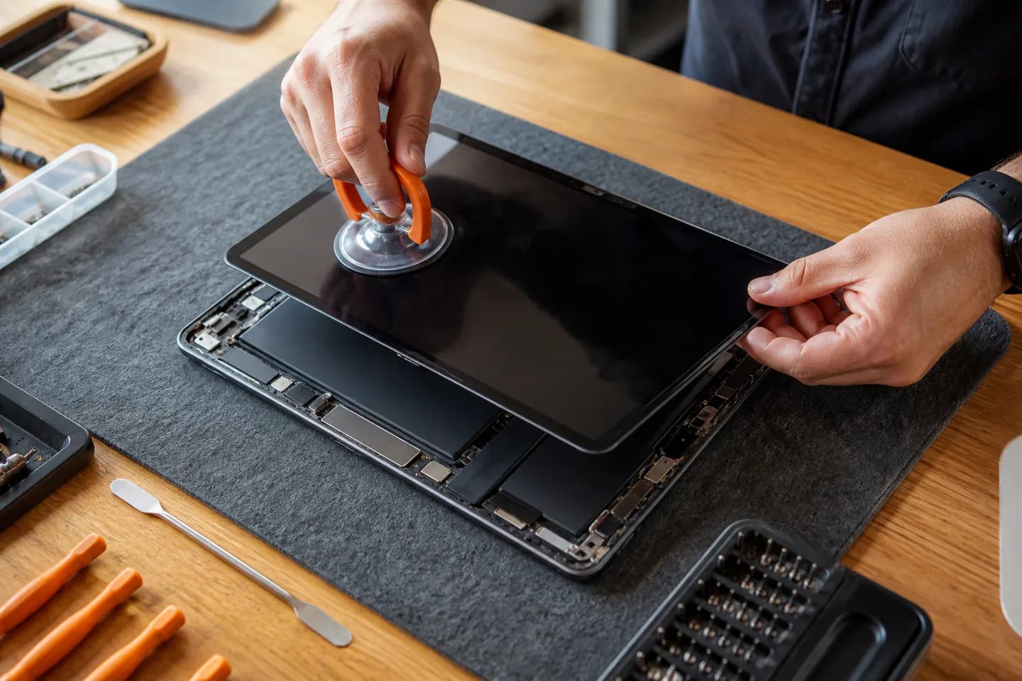 Technician lifting a tablet display during a screen repair